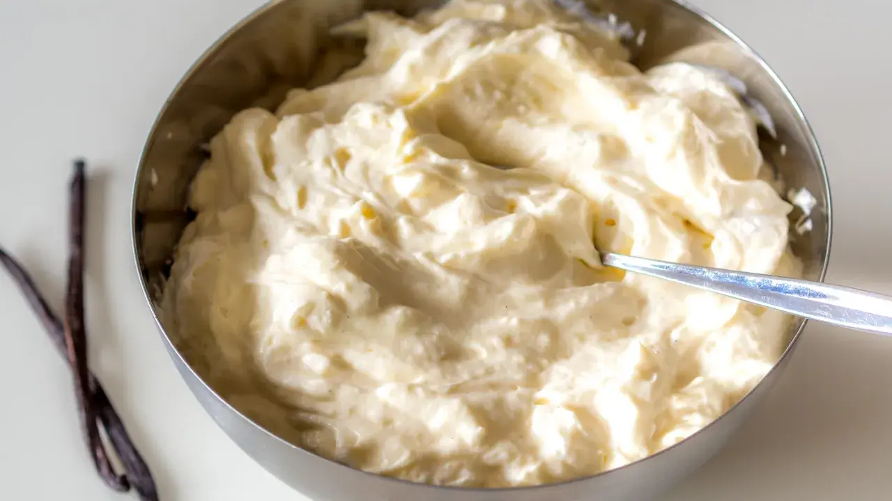 Schüssel mit cremiger, italienischer Vanillecreme, daneben zwei Vanilleschoten.