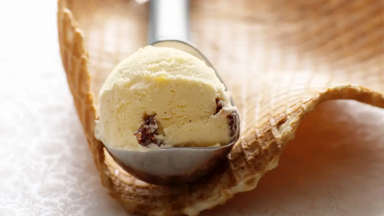 Ein Löffel cremiges Malaga Eis mit Rosinen, bereit für ein Waffelhörnchen. Ein einfaches Malaga Eis Rezept für den Sommer.
