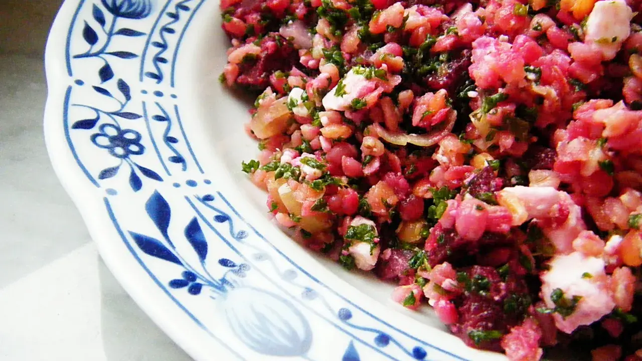 Bunter rote Bete Salat mit Linsen und Feta, garniert mit frischer Petersilie, serviert auf einem Teller mit blauem Blumenmuster.