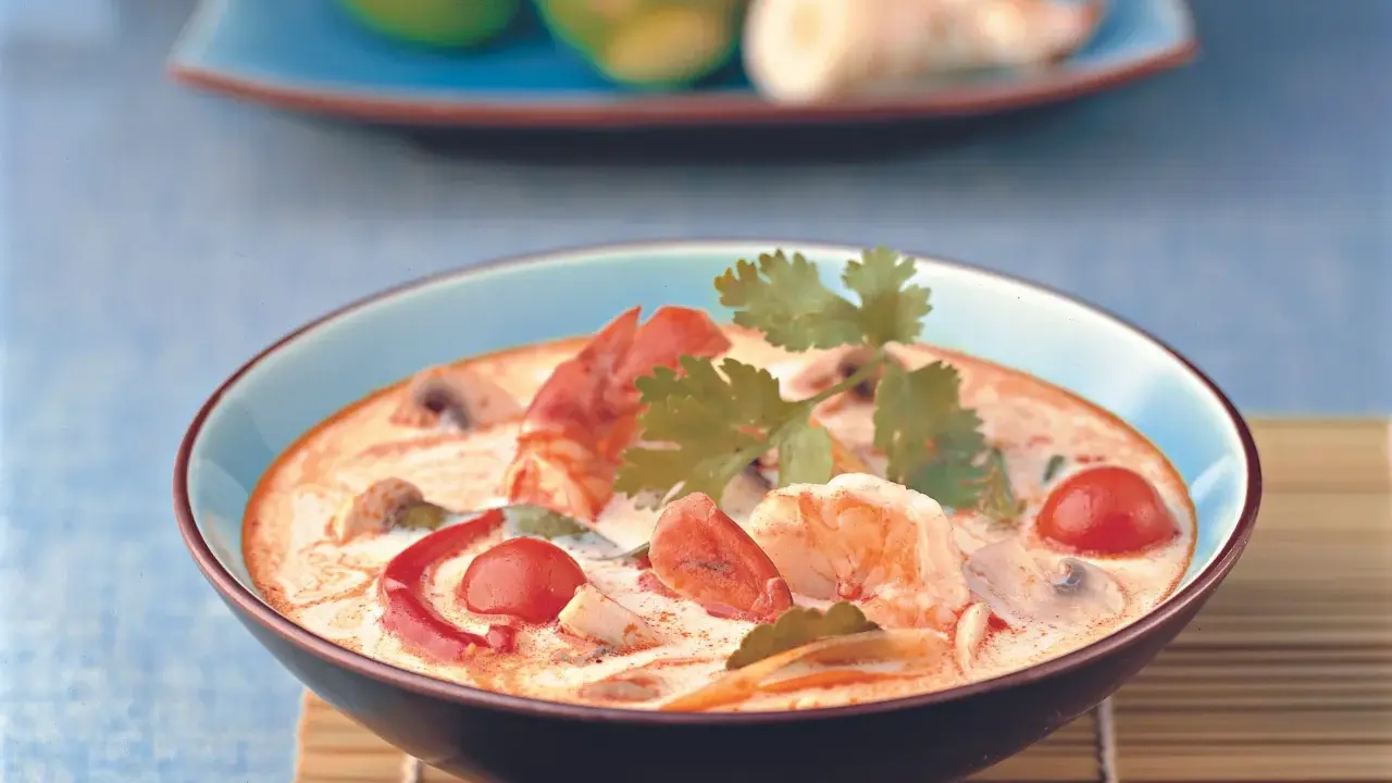 Eine cremige garnelensuppe asiatisch mit Garnelen, Pilzen und Tomaten, garniert mit Koriander.