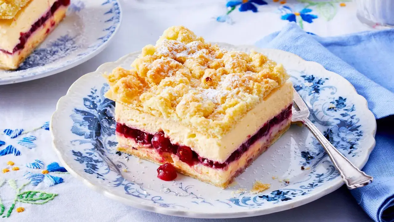 Ein Stück bester Pudding-Kuchen mit Kirschen und Streuseln auf einem blumengemusterten Teller.