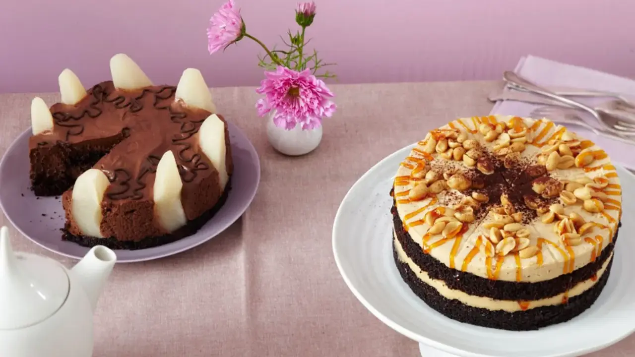 Zwei Torten auf einem Tisch: eine Schokoladen-Birnen-Torte und eine köstliche Erdnuss Torte mit Karamell und Nüssen.