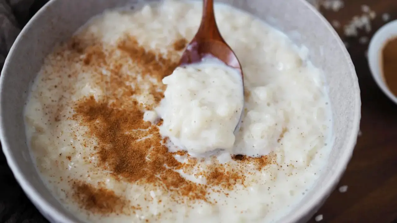Cremiger Milchreis mit Zimt, der auf einem Holzlöffel serviert wird. Das Waschen des Milchreises ist ein wichtiger Schritt für die perfekte Konsistenz.