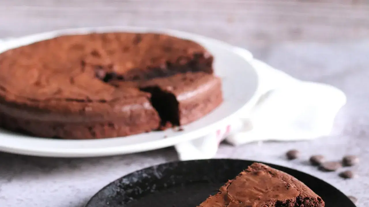 Ein Stück vom originalen Tarte au Chocolat Rezept, saftig und schokoladig, auf einem schwarzen Teller.