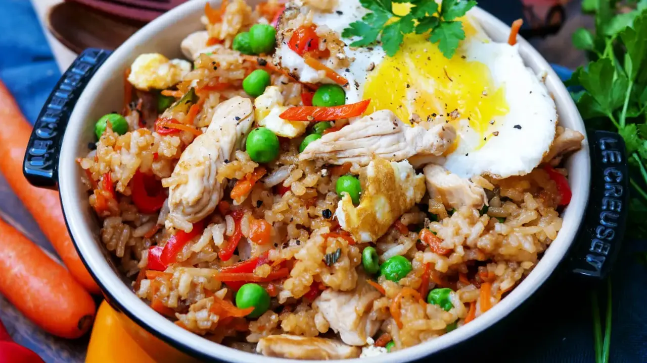 Ein köstliches Nasi Goreng Rezept original: Reis mit Hühnchen, Erbsen, Karotten, Paprika und Spiegelei, garniert mit Petersilie.