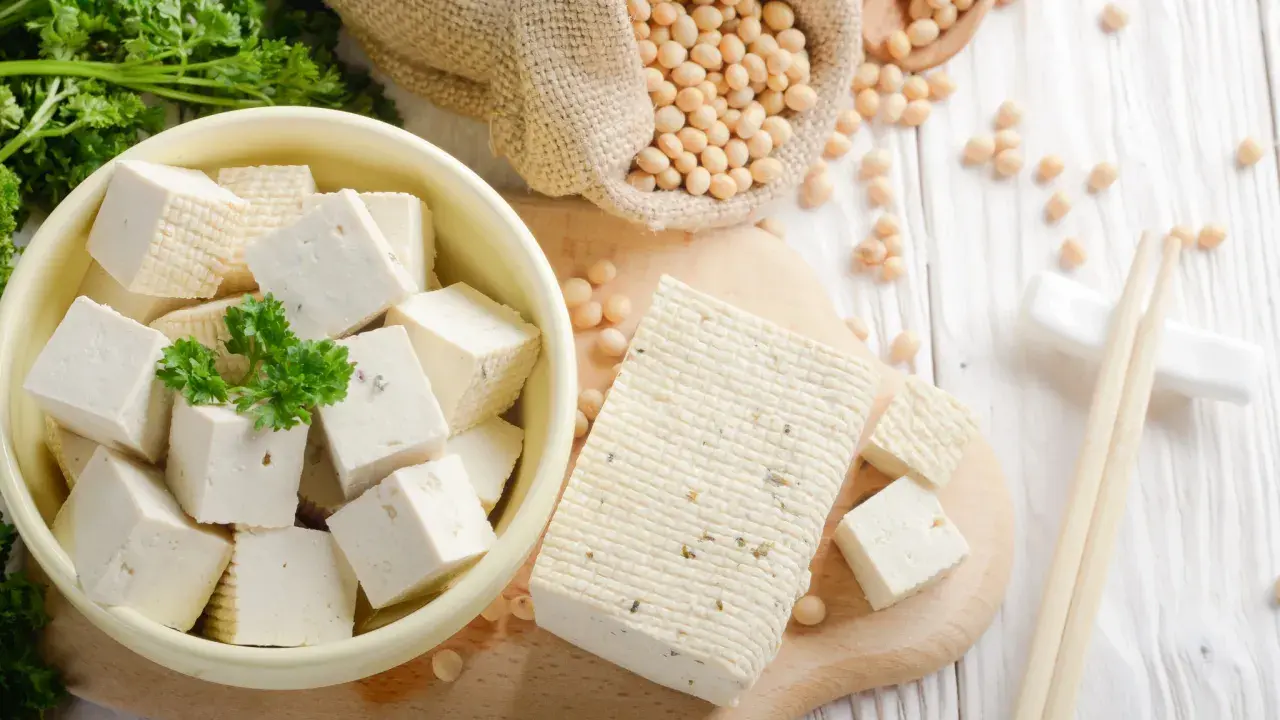 Frischer Tofu, ein toller Fleischersatz, liegt neben Sojabohnen und Petersilie.