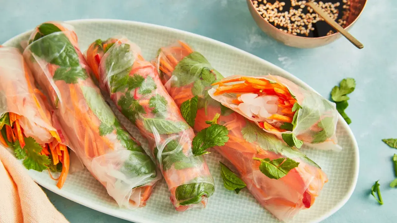 Frische Sommerrollen mit knackigem Gemüse und Garnelen, perfekt für ein leichtes Sommerrollen Rezept original. Dazu eine Dip-Schale mit Sesam.