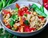 Schüssel mit Nudeln, Erdnüssen, Zuckerschoten, Karotten und Paprika. Ein leckeres Asia Salat Rezept.