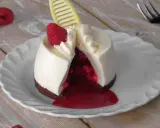 Ausgefallene Desserts zum Vorbereiten: Ein cremiges Dessert mit Himbeersauce und frischer Himbeere, dekoriert mit einem gelben Schokoladen-Detail.