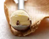 Ein Löffel cremiges Malaga Eis mit Rosinen, bereit für ein Waffelhörnchen. Ein einfaches Malaga Eis Rezept für den Sommer.