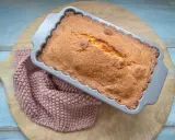 Frisch gebackener, goldbrauner quatre quarts in einer Kastenform, daneben ein rosafarbenes Stricktuch.