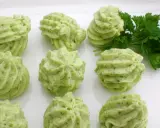 Grüne Kräuterbutter-Tuffs auf weißer Platte, perfekt für Ihre butter rezepte. Frische Petersilie daneben.