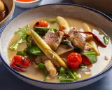 Eine dampfende Schüssel mit **thai Fischsuppe**, garniert mit Kirschtomaten, Kräutern und Zitronengras.