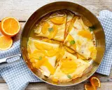 Crêpes Suzette im Originalrezept: zarte Pfannkuchen in Orangensauce mit frischen Orangenspalten und Minze garniert.