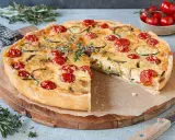 Eine köstliche, sommerliche Quiche mit Kirschtomaten und Zucchini, garniert mit frischem Thymian.