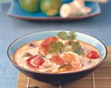 Eine cremige garnelensuppe asiatisch mit Garnelen, Pilzen und Tomaten, garniert mit Koriander.