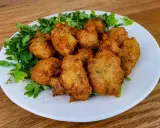 Knusprige Accras de Morue, goldbraun frittiert und mit frischer Petersilie garniert, auf einem weißen Teller.