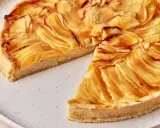 Eine köstliche Tarte au Pomme mit karamellisierten Apfelscheiben auf einem knusprigen Boden, auf einem rustikalen Teller.