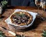 Herzhafte Tarte Tatin mit karamellisierten Zwiebeln und frischen Kräutern, serviert mit Weißwein.
