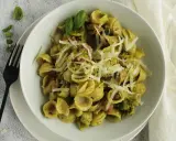 Orecchiette-Pasta mit grünem Pesto, Speck und geriebenem Parmesan. Ein köstliches Gericht, das zeigt, wie vielseitig Rezepte mit Pistazienmus sein können.