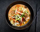 Ein aromatischer Thai Curry Rind mit Reis, Karotten und frischen Kräutern, garniert mit Limette.