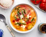 Eine dampfende Schüssel seidentofu suppe mit Zucchini und Frühlingszwiebeln, garniert mit Chiliöl. Daneben eine Schüssel Reis und ein Glas Chiliöl.