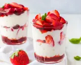 Zwei Gläser mit Erdbeer Mascarpone Creme, geschichtet mit frischen Erdbeeren und Erdbeersauce, garniert mit Minze.