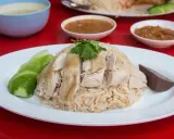 Khao Man Gai: gedämpfter Reis mit zartem Hühnchen, Gurkenscheiben und einer Blutwurstscheibe, garniert mit Koriander.