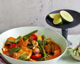Ein köstliches Panang Curry mit Fisch, Kürbis, grünen Bohnen und Tomaten, garniert mit frischem Basilikum und Limettenspalten.