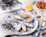 Calissons rezept: Süße Mandelkekse mit weißer Glasur auf blau-weißem Teller, garniert mit Lavendel und Mandeln.