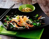 Ein bunter Papaya Salat vietnamesisch mit Karottenstreifen, Kräutern und gerösteten Erdnüssen.