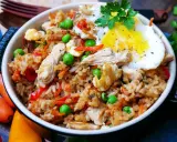 Ein köstliches Nasi Goreng Rezept original: Reis mit Hühnchen, Erbsen, Karotten, Paprika und Spiegelei, garniert mit Petersilie.