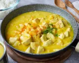 Ein köstlicher Curry mit Ananas und Hähnchenstücken in einer cremigen gelben Sauce, garniert mit Petersilie und Paprikapulver.