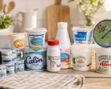 Eine Auswahl an Milchprodukten, darunter verschiedene Becher mit fromage blanc, Crème fraîche und Joghurt, auf einem Holztisch.