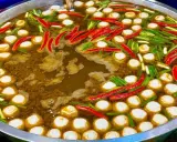 Ein dampfender Topf mit Fleischbällchen, Chilis und Frühlingszwiebeln – ein Einblick in die vielfältigen Esskulturen weltweit.