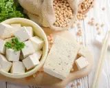 Frischer Tofu, ein toller Fleischersatz, liegt neben Sojabohnen und Petersilie.