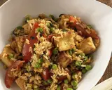 Herzhafter pilaw reis mit gebratenem Tofu, Erbsen und Tomatenstücken in einer weißen Schüssel.