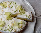 Eine köstliche Limetten Tarte mit luftiger Baiserhaube, garniert mit frischen Limettenscheiben und Zesten. Ein Stück wird gerade serviert.