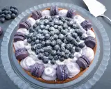 Eine Macaron Torte mit Blaubeeren und lila Macarons, bestäubt mit Puderzucker.