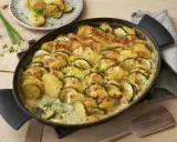 Herzhafte zucchini kartoffel rezepte: überbackene Scheiben aus Zucchini und Kartoffeln in cremiger Sauce, garniert mit Schnittlauch.