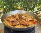 Eine köstliche Paella mit Hähnchenstücken und Paprika, die zeigt, was ist paella: ein herzhaftes Reisgericht.