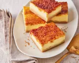 Köstliche Stücke Creme Brulee Kuchen mit karamellisierter Zuckerkruste auf einem Teller, daneben eine goldene Tortenheber.