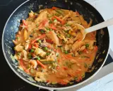 Ein köstliches veganes Curry mit viel Gemüse wie Karotten, Erbsen und Bambussprossen wird in einer Pfanne zubereitet.