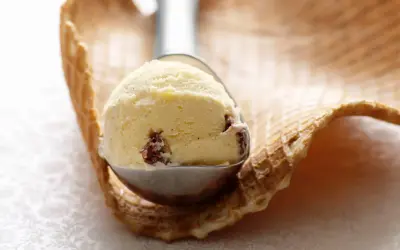 Ein Löffel cremiges Malaga Eis mit Rosinen, bereit für ein Waffelhörnchen. Ein einfaches Malaga Eis Rezept für den Sommer.