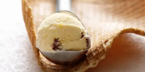 Ein Löffel cremiges Malaga Eis mit Rosinen, bereit für ein Waffelhörnchen. Ein einfaches Malaga Eis Rezept für den Sommer.
