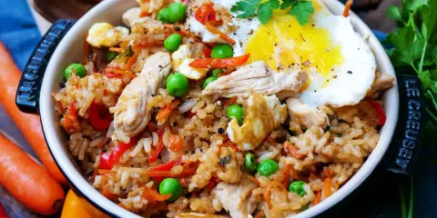 Ein köstliches Nasi Goreng Rezept original: Reis mit Hühnchen, Erbsen, Karotten, Paprika und Spiegelei, garniert mit Petersilie.