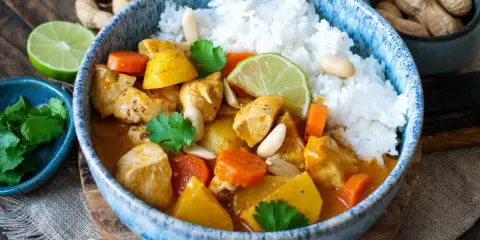 Ein köstlicher Massaman Curry mit Hühnchen, Kartoffeln, Karotten und Erdnüssen, serviert mit Reis. Der Massaman Curry Geschmack ist intensiv und aromatisch.