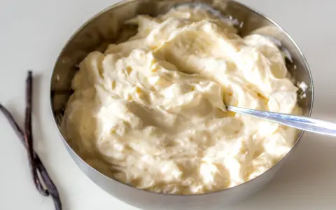 Schüssel mit cremiger, italienischer Vanillecreme, daneben zwei Vanilleschoten.