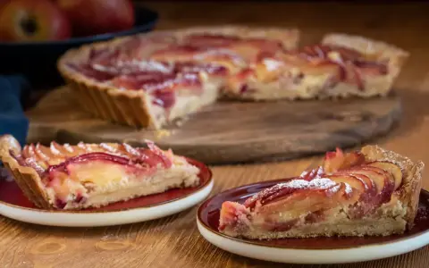Saftige Apfeltarte mit roten Apfelscheiben, bestäubt mit Puderzucker. Ein köstliches Apfeltarte Rezept für Genießer.