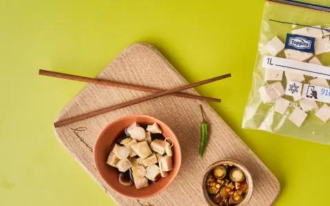 Vorbereitung für tofu einfrieren: gewürfelter Tofu in Schüssel mit Soße, Stäbchen, Chili und Beutel mit gefrorenem Tofu.